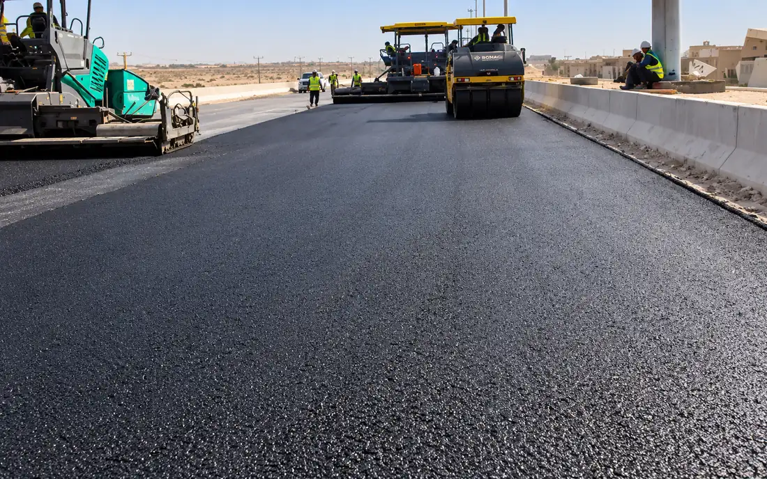Asphalt paver and roller laying the surface course on a wide carriageway
