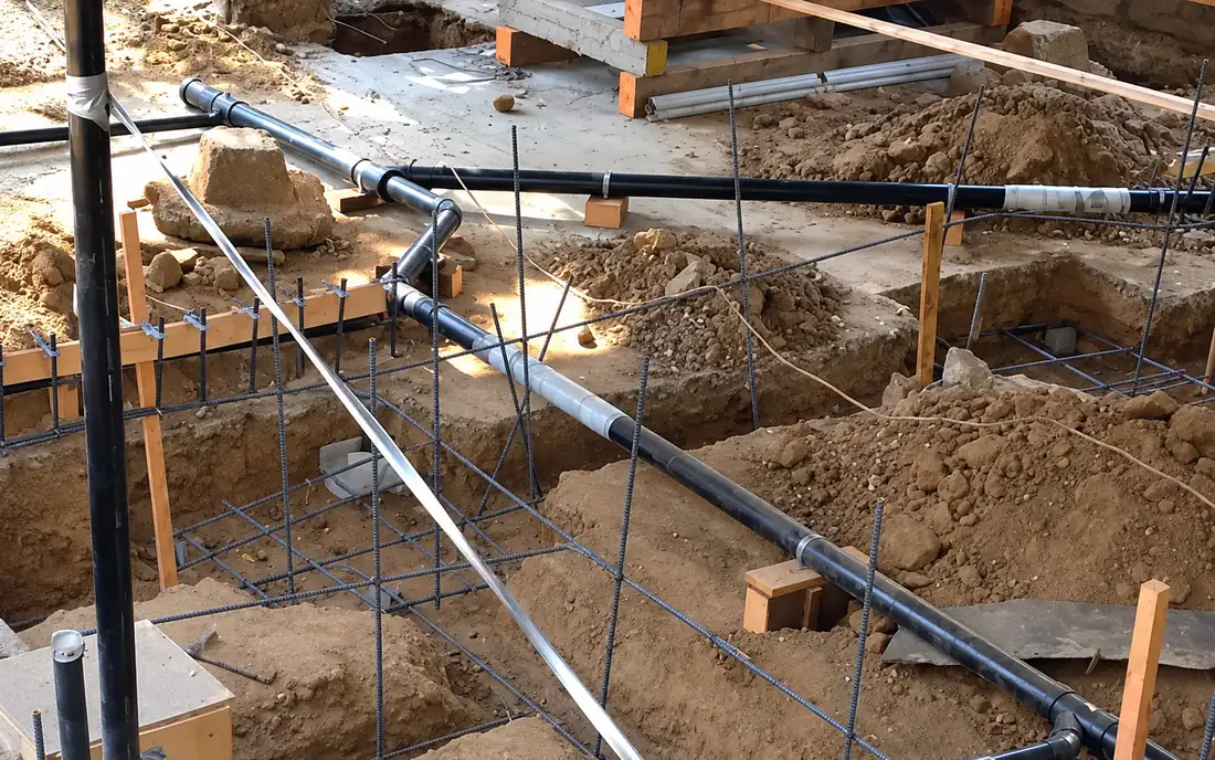 Buried drainage pipework over reinforcement and formwork before the pour